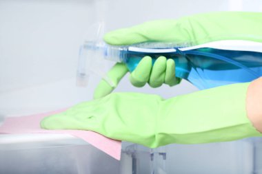 Ellerinde eldiven sünger ve deterjan temizlik buzdolabı şişe