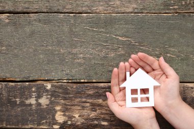 Kağıt ev ahşap arka plan üzerinde tutan eller