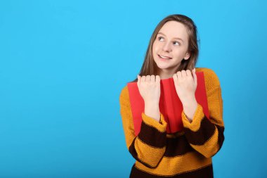 Mavi arka plan üzerinde kırmızı kitap ile genç kız