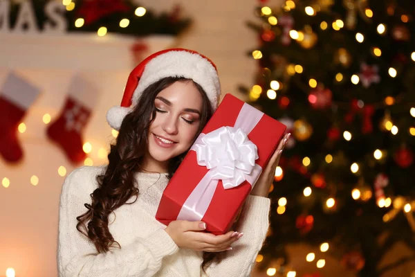 Молодая Женщина Шляпе Санты Подарочной Коробкой Возле Рождественской Елки Дома — стоковое фото