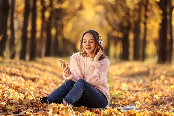 Mooi Meisje Zit Met Hoofdtelefoons Smartphone Herfst Park — Stockfoto