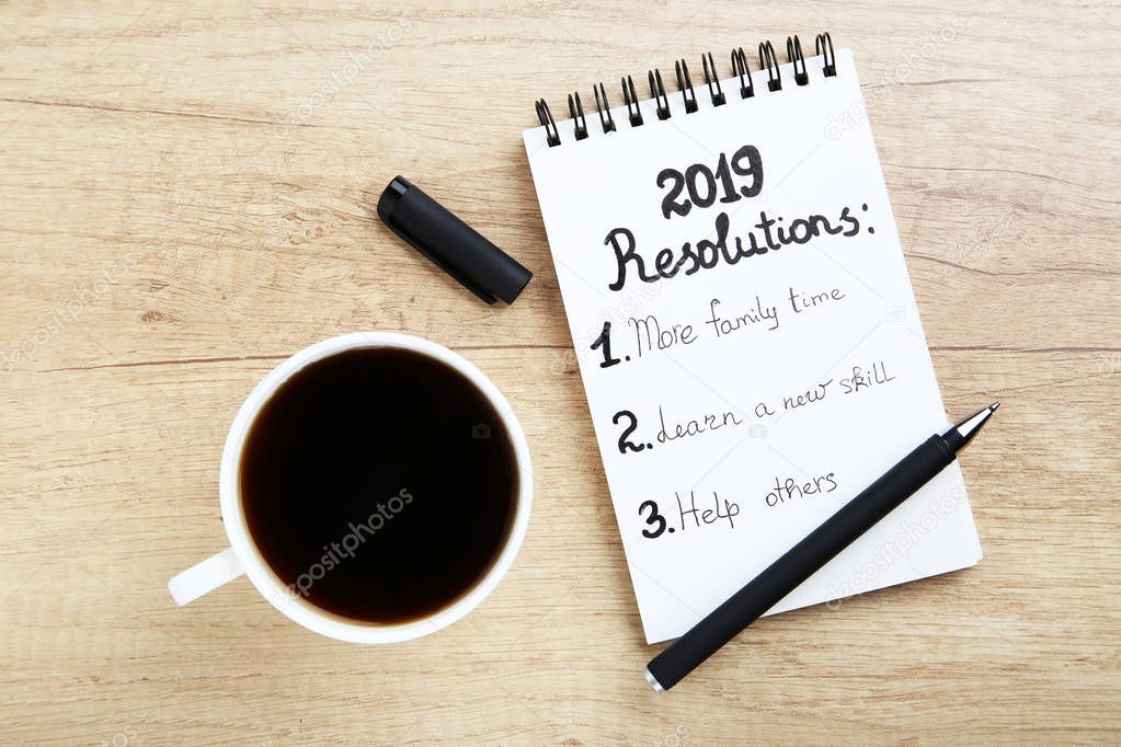 Inscription 2019 resolutions in notepad with pen and cup of coffee