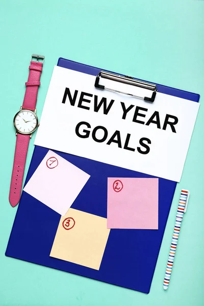 New year goals on sheet of paper with clipboard, pen and wrist watch