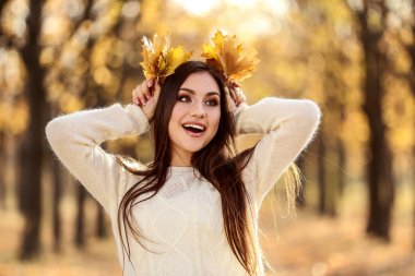 Kuru akçaağaç tutan güzel kadın sonbahar parkta yapraklar