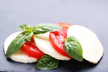 Mozzarella peyniri, domates ve fesleğen yaprakları gri arka plan üzerinde