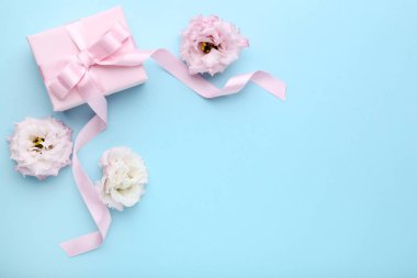 Hediye kutusu ile mavi arka plan üzerinde şerit ve eustoma çiçekler