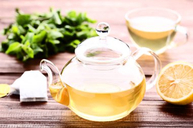 Ahşap masa üzerinde cam çaydanlık limon ve nane yaprakları