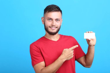 Mavi arka plan üzerinde boş beyaz kart ile genç adam