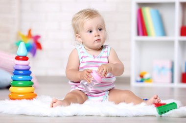 Beyaz halı üzerinde oturan şişe ile kız bebek