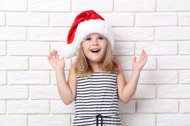 Tuğla üzerinde santa şapkalı küçük kız duvar arka plan