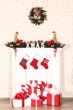 Beyaz şömine hediye kutuları ve tuğla duvar arka plan üzerinde çelenk ile dekore edilmiştir.