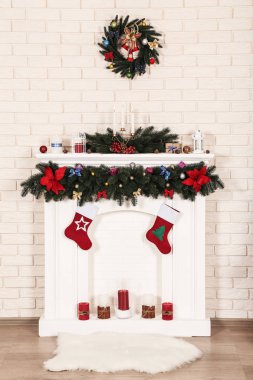 Beyaz şömine tuğla duvar arka plan üzerinde çelenk ile dekore edilmiştir.