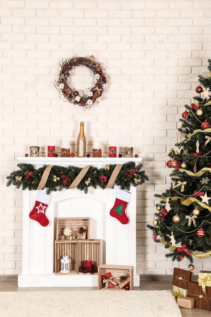 Decorated fireplace near christmas tree on brick wall background