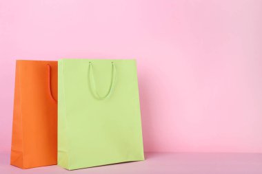 Pembe arka planda renkli kağıt alışveriş torbaları
