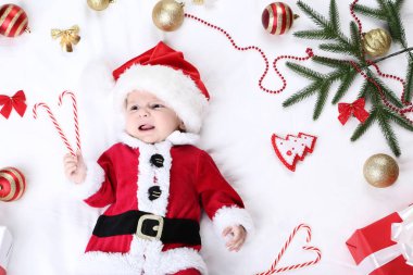 Kırmızı kostümlü yatakta yatarken Noel süslemeleri ile küçük çocuk