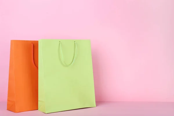 Colorful paper shopping bags on pink background