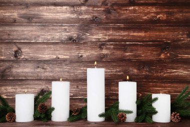 Köknar ağaç dalları ve koniler kahverengi zemin üzerine beyaz Noel mumlar