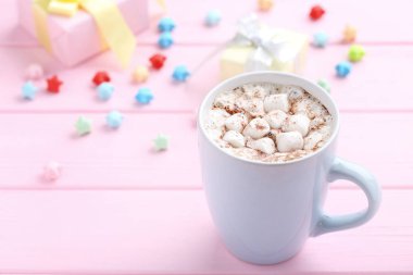 Kapuçino Kupası ve kağıt yıldız pembe ahşap masa üstünde marshmallow ile