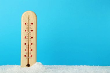 Mavi arka plan üzerinde karda ahşap termometre