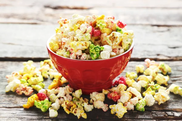 Colorful popcorn in bowl on wooden table