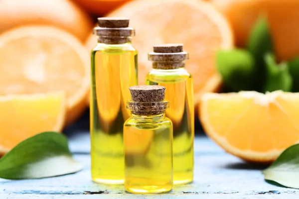 Aceite Naranja Botellas Con Hojas Verdes Sobre Mesa Madera Azul —  Fotos de Stock