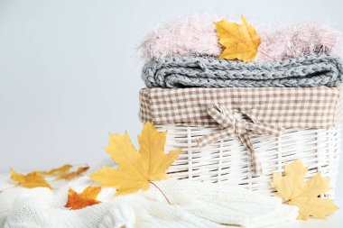 Gri arka plan üzerinde katlanmış kazak ve akçaağaç sepetle eşarp yığını bırakır