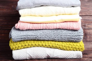 Kahverengi ahşap zemin üzerinde katlanmış kazak yığını