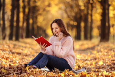 Sonbahar park kitap ile oturan genç güzel kız