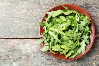 Plaka gri ahşap masa üzerinde yeşil roka yaprakları