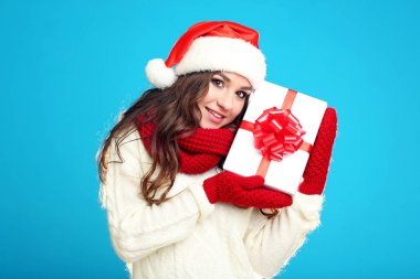 Hediye kutusu mavi arka plan üzerinde tutan güzel genç kız