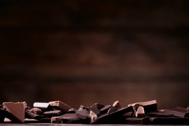 Koyu arka plan üzerinde ahşap masa üzerinde çikolata parçaları