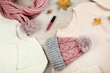 Örme kazak atkı, dudak parlatıcısı ve yerdeki sonbahar yaprakları