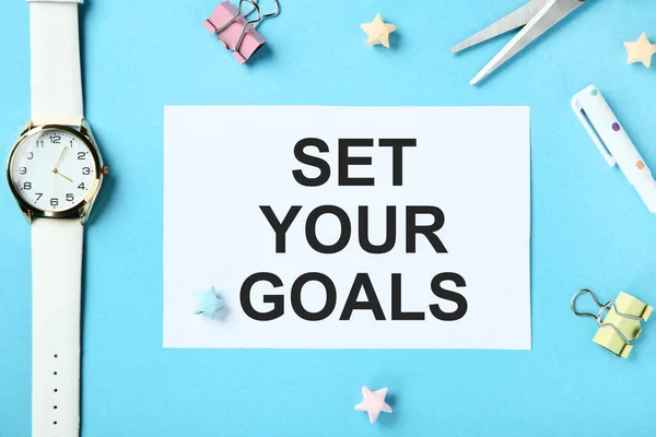 Set your goals on sheet of paper with wrist watch, clips and colorful stars