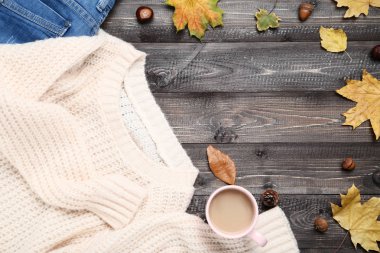 Örme kazak kot ile coffes ve Sonbahar Kupası tahta masada bırakır.