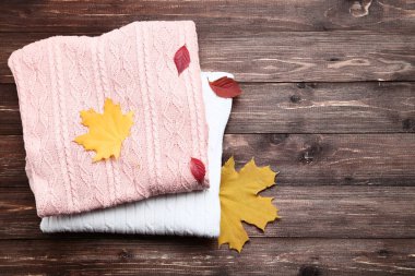 Kazak ile sonbahar yaprakları kahverengi ahşap masa üzerinde katlanmış