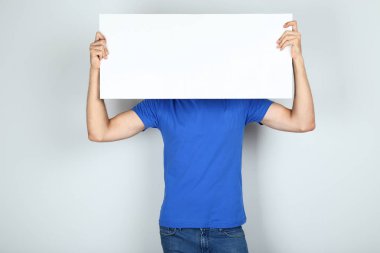 Pano gri arka plan üzerinde tutan genç adam