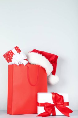 Alışveriş çantası hediye kutuları ve gri arka plan üzerinde santa şapka ile