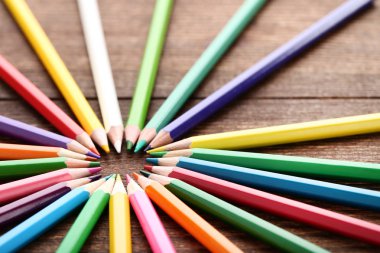 Kahverengi ahşap masa üzerinde bir dairede renkli kalemler