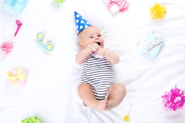 Oyuncak ve hediye kutuları beyaz yatakta yatarken bebek çocuk