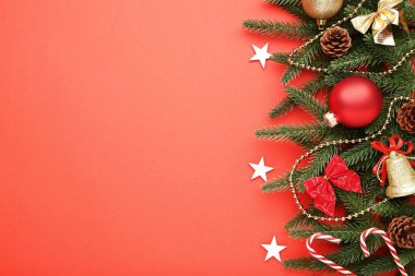 Kırmızı zemin üzerine süslemeleri ile Noel köknar ağacı dalları