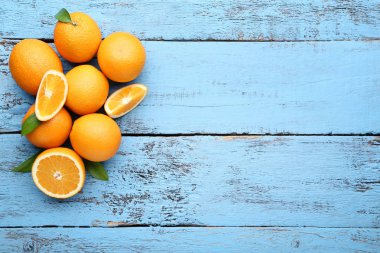 Mavi ahşap masa üzerinde yeşil yaprakları ile turuncu meyve