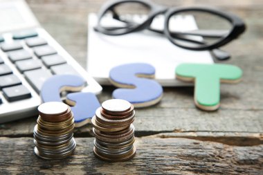 Sikke ve ahşap masa üzerinde kelime Gst hesap makinesi ile yığını