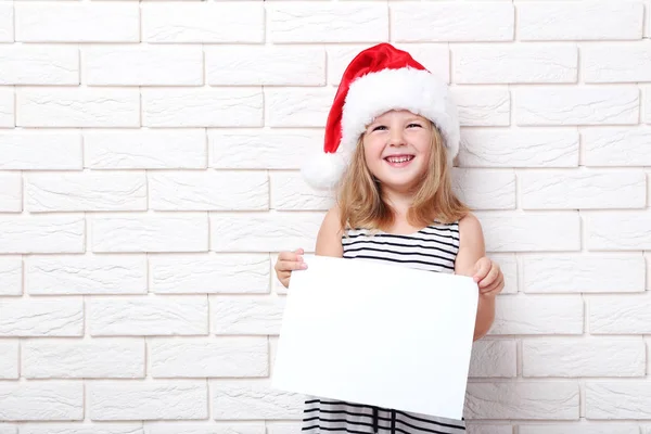 Menina Santa Chapéu Segurando Folha Papel Branco Fundo Parede Tijolo — Fotografia de Stock