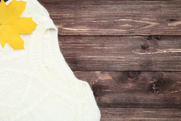 Folded sweater with maple leaf on brown wooden table