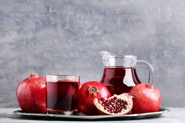 石榴水果和果汁在玻璃和水罐在灰色的木桌上 — 图库照片
