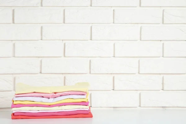 Stack of folded clothes on brick wall background