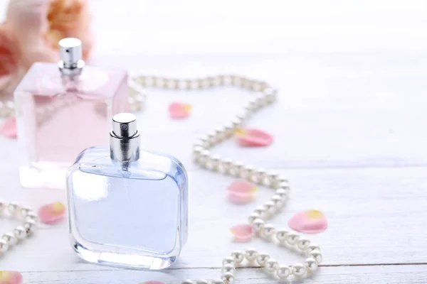 Parfümflaschen Mit Blütenblättern Und Perlen Auf Holztisch — Stockfoto