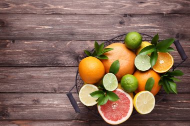 Narenciye kahverengi ahşap masa üzerinde sepet içinde yeşil yaprakları ile