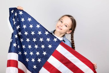 Bir Amerikan bayrağı gri arka plan üzerinde tutan genç kız