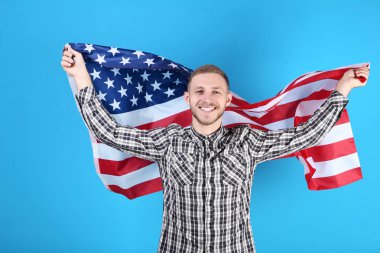Genç adam bir Amerikan bayrağı mavi arka plan üzerinde tutan